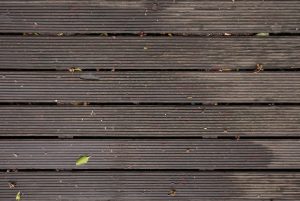 Wet and dirty composite decking with leaves and some dirt