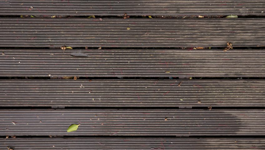 Wet and dirty composite decking with leaves and some dirt