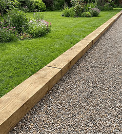 3m treated sleepers used as edging between gravel driveway and garden